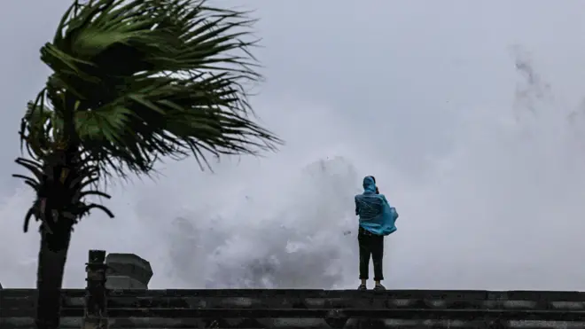 台灣基隆海旁一名身穿藍色雨衣的民眾在岸邊觀看巨浪滔天（11/7/2026）
