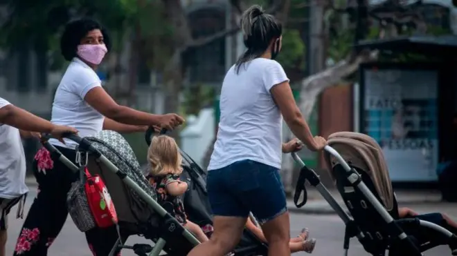 Três babásbets betanocamisa branca empurrando carrinho na rua