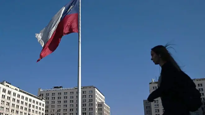 Una mujer camina junto a la bandera de Chile cerca del Palacio de La Moneda, en Santiago.