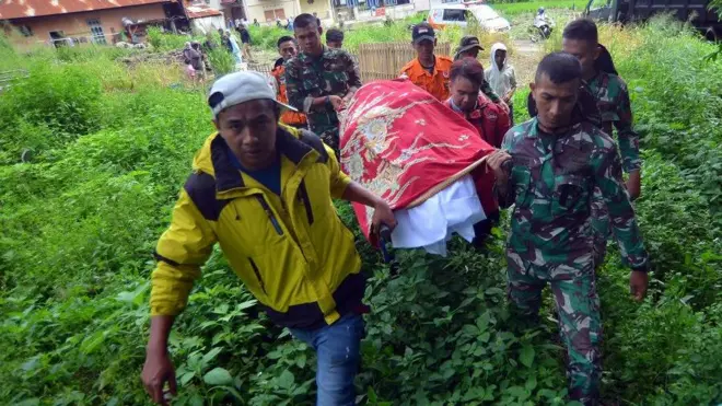 Relawan bencana bersama prajurit TNI dan warga menggotong jenazah korban banjir bandang yang baru ditemukan di Jorong Galuang, Nagari Sungai Pua, Agam, Sumatera Barat, Selasa (14/5/2024).