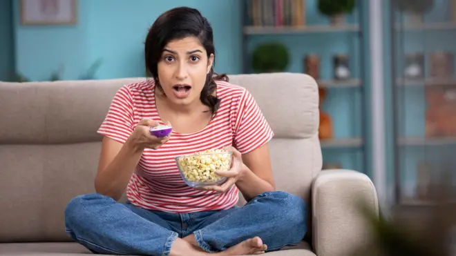 टीव्हीसमोर बसून खाणारी महिला