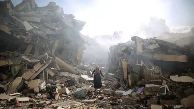 A resident gets upset as she walks amid near the rubble of residential buildings after Israeli airstrikes at Al Zahra neighbourhood