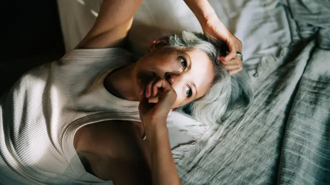 Mulher deitada na cama, acordada