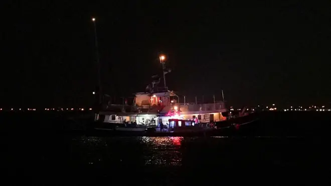 سفينة تابعة لأسطول الصمود العالمي تطفو في المياه بينما تقوم قوارب الحرس الوطني البحري التونسية بالتفتيش في ميناء سيدي بوسعيد، تونس