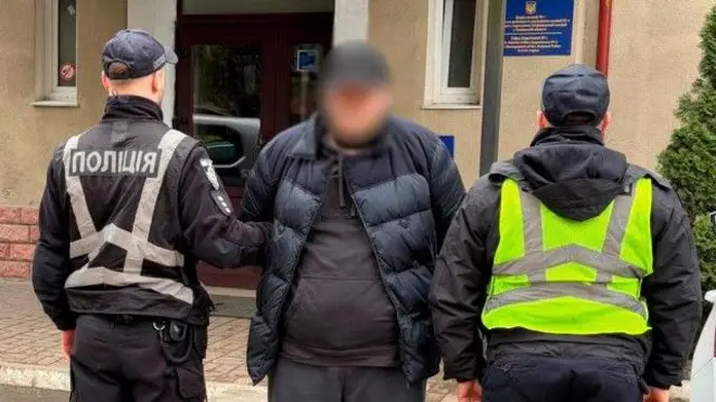 Двоє поліцейських тримають чоловіка за руки. У нього заблюрене лице 