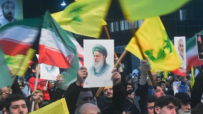 شرکت‌کنندگان در یک تجمع اعتراضی در ۲۶ ژانویه ۲۰۲۶ در بیروت، لبنان، به سخنرانی نعیم قاسم، دبیرکل حزب‌الله، گوش می‌دهند. گروهی در منطقه ضاحیه گرد هم آمده‌اند و با در دست داشتن پرچم‌های حزب‌الله و ایران و همچنین تصاویر آیت‌الله علی خامنه‌ای، رهبر جمهوری اسلامی ایران، به احتمال حمله آمریکا به ایران که از سوی دونالد ترامپ، رئیس‌جمهور آمریکا، اعلام شده، اعتراض می‌کنند. این تجمع برای اعلام همبستگی با علی خامنه‌ای و مردم ایران برگزار شده است.