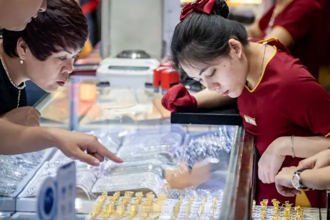 Một nhân viên nữ (bên phải) hỗ trợ khách hàng nữ bên trong một cửa hàng trang sức trong dịp Tết Nguyên đán tại Hà Nội vào năm 2024 