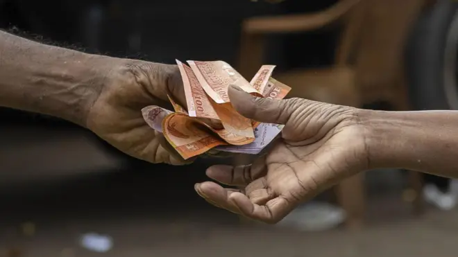 Close-up of a person handing over Sri Lankan rupee banknotes