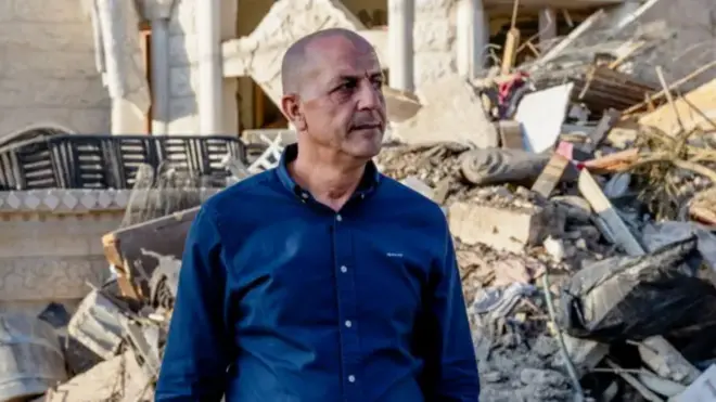 Adel Khatib se encuentra frente a un fondo de escombros.