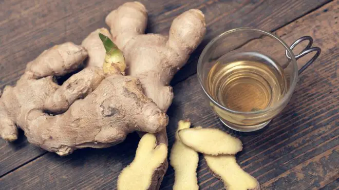 Àwòrán atalẹ̀ àti ife omi kan tí omi atalẹ̀ wà nínú rẹ̀