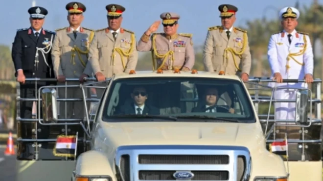 الرئيس السيسي يرتدي زياً عسكريا ويؤدي التحية العسكرية من على عربة عسكرية مكشوفة وبجواره قادة الجيش المصري في افتتاح مبنى الأوكتاغون