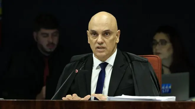 Alexandre de Moraes usando toga preta e olhando para a câmera durante sessão do STF