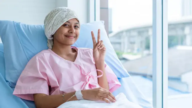 कॅन्सर रुग्ण हॉस्पिटलमधल्या बेडवरून vicrory साईन दाखवताना. 