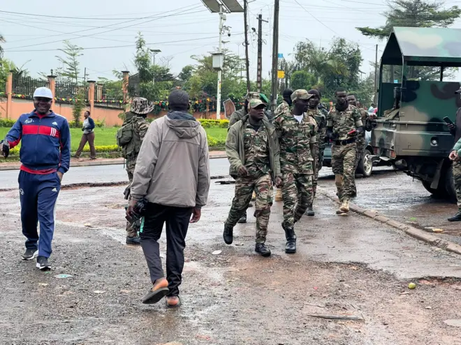 Une rue de Bamenda avec des hommes en uniforme militaire et un jeep.