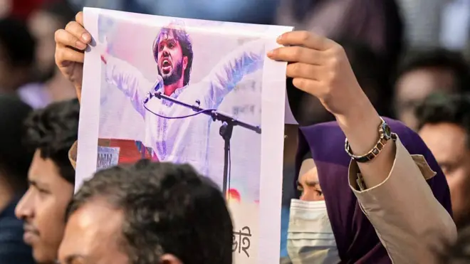 শহীদ মিনারে সভায় ওসমান হাদির ছবি দেখা যাচ্ছে তার একজন সমর্থকের হাতে