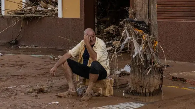 Um homem sentadosporting bet ioslocal tomado pela lama,sporting bet iosPaiporta