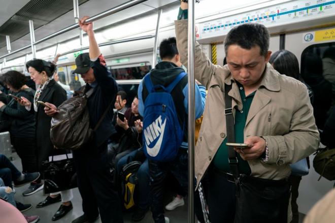 ركّاب ينظرون إلى هواتفهم في مترو بكين الصين
