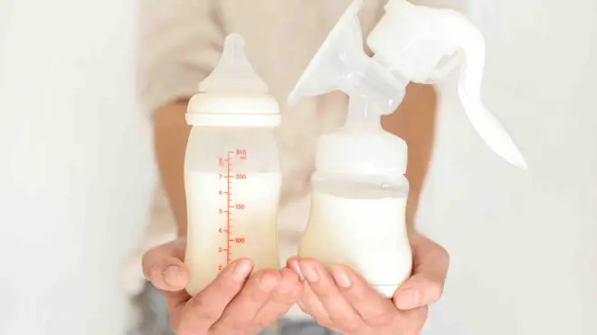 A picture of a woman holding a breast milk bottle and a milk pump