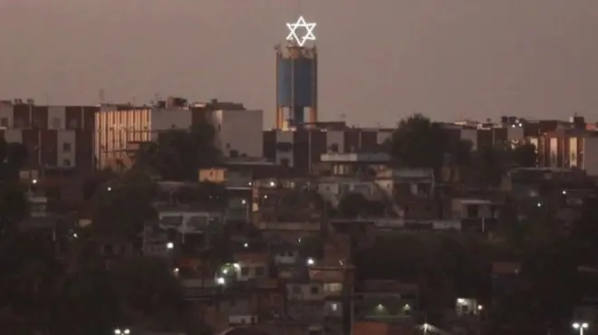 Imagem de casas no Complexo de Israel. A estrela de Davi está no alto de uma torre
