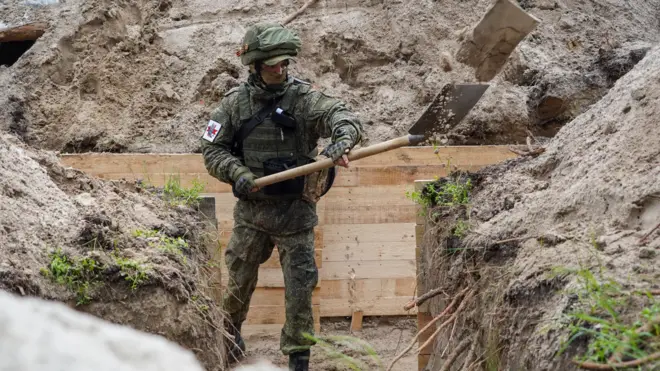 человек в камуфляже копает окоп