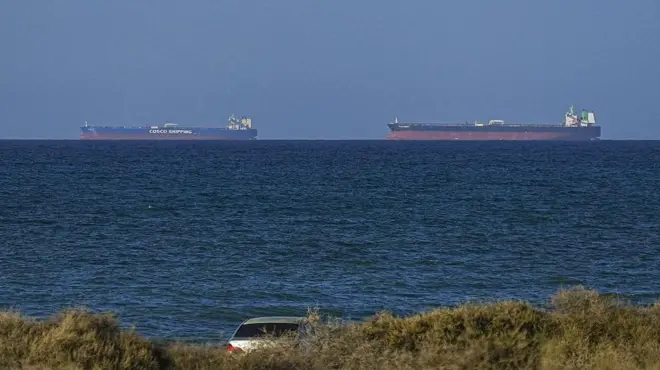 Karadan çekilmiş fotoğrafta uzakta iki büyük tanker görülüyor. Tankerler Hürmüz Boğazı'ndan geçmek için bekliyor.
