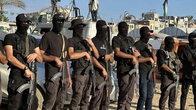 Бойцы ХАМАС сна улице в секторе Газа. Они в балаклавах и вооружены автоматами.