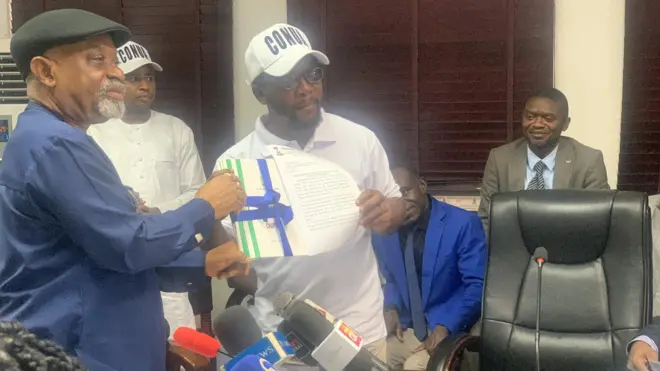 MInisita fọrọ osise n fun ọkan lara awọn ẹgbẹ tuntun naa ni iwe ẹri