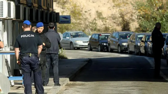 Nekoliko muškaraca u uniformama policije Kosova na prelazu Jarinje, u daljini se vidi kolona automobila