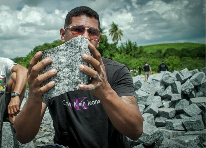Trabalhador de pedreira segura uma pedra nas mãos