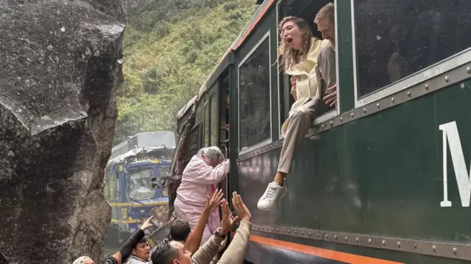 Varias personas intentan ayudar a las víctimas que intentan ponerse a salvo desde un tren colisionado