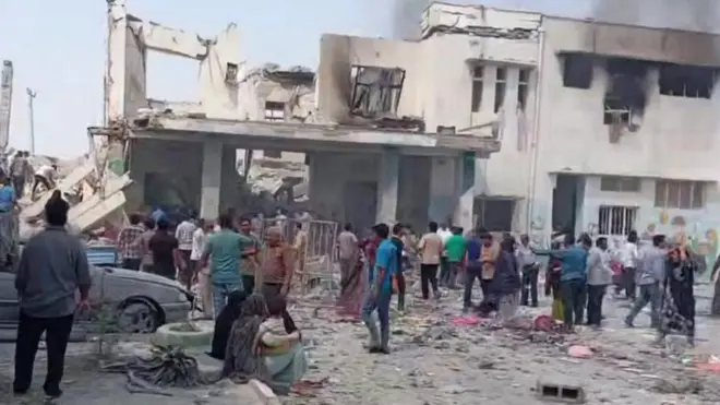 تصویری از محوطه بیرونی مدرسه که روز زمین آوار است و مردم نگران