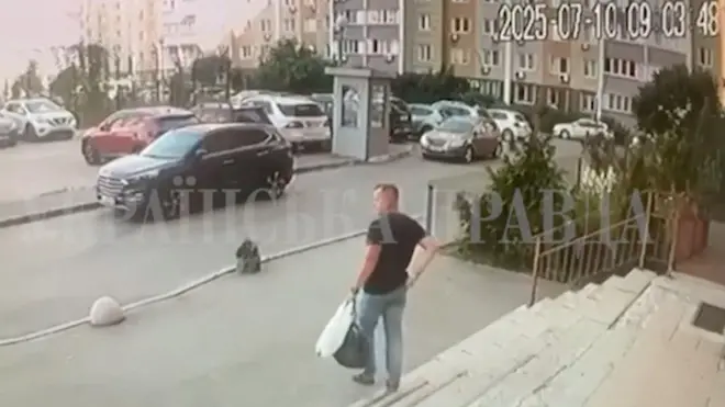 Umugabo wambaye ipantalo y'ikoboyi n'umupira wijimye w'amaboko magufi afite igikapu gito cya plastike n'ikindi gikapu kijyamo ibintu binyuranye, atwaye ibikapu byombi mu kuboko kumwe, arimo kugenda ava mu nyubako, yerekeza ahaparikwa imodoka, i Kyiv, muri Ukraine.