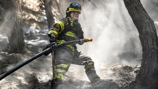 رجل إطفاء يخمد حريقاً في غابة