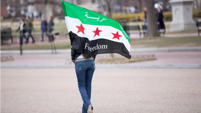 صورة لرجل يحمل العلم السوري