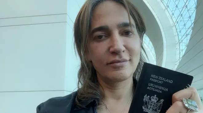 سرین بدیعی در حالی که پاسپورت نیوزلند در دست دارد و به نظر می‌آید در فرودگاه نشسته است