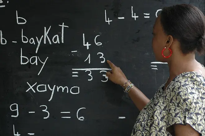 Une femme face au tableau dans une classe