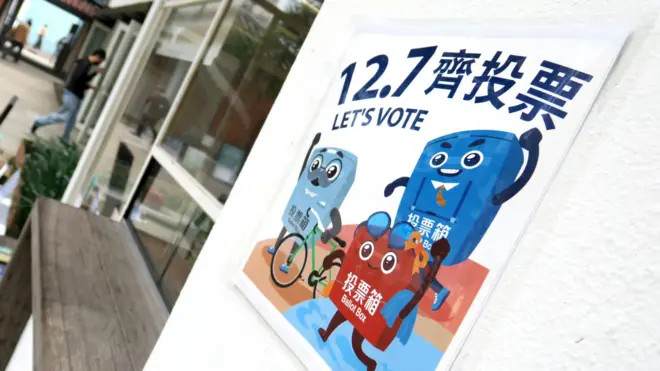 香港炮台山“油街实现”艺术空间内一张贴在墙壁上的“12.7齐投票”大尺码宣传贴纸(BBC中文图片4/12/2025)