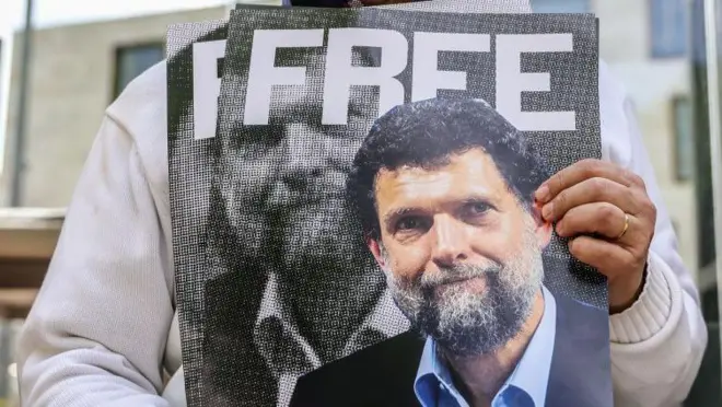 FREE (serbest bırakılsın) yazılı posterde Osman Kavala'nın fotoğrafı var, posteri tutan el görünüyor.