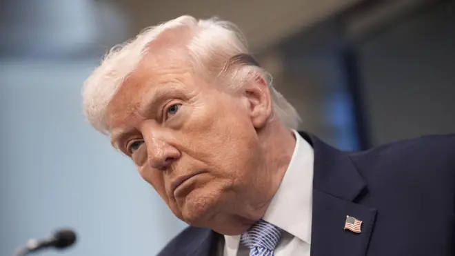 ABD Başkanı Donald Trump üzerinde bir takım elbiseyle basın toplantısında gazetecilere doğru bakıyor