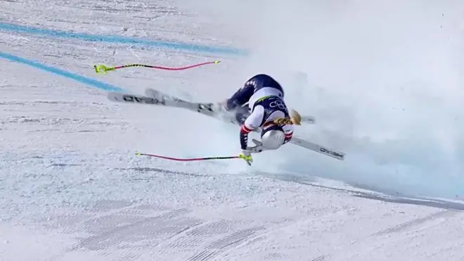 Гірськолижниця у процесі падіння на трасі для швидкісного спуску.