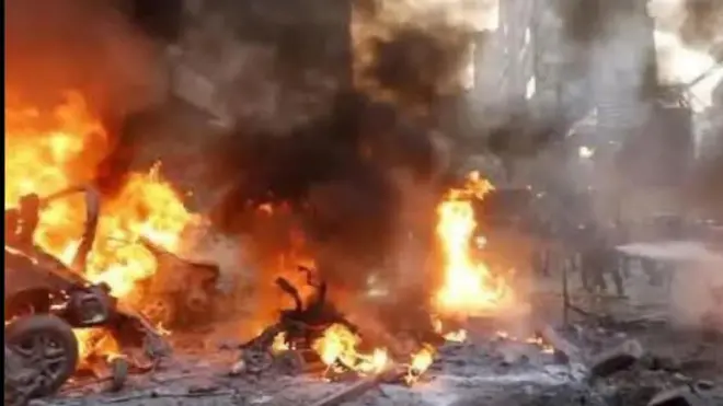 Iná ń jó sókè fíofío pẹlu èéfín ńlá níbi tí àdó olóró tí bù nínú Mọsalasi, ọ̀pọ̀ èèyàn dúró, wọn ń wò rán.