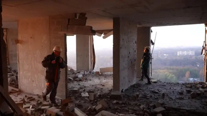 Два спасателя на разрушенном высоком этаже здания.