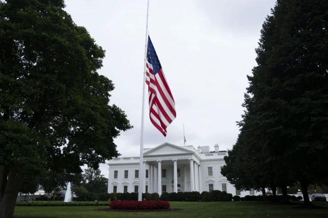 Bandeira dos EUA a meio-mastro, com Casa Branca vita ao fundo