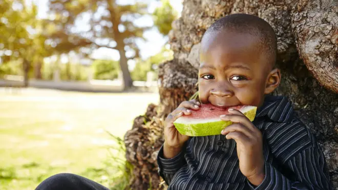 One litle boy dey eat watermelon