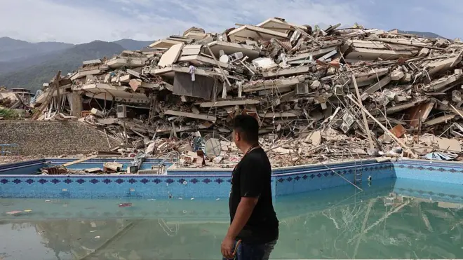 Residente de La Guaira camina ante un edificio completamente destruido
