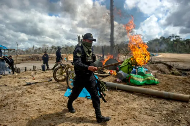 Un policía peruano camina con una tea en un operativo en una mina ilegal en la selva peruana.