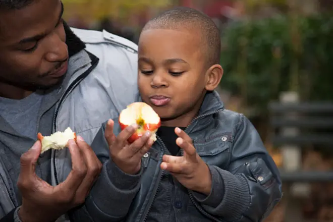 Un enfant mangeant une pomme avec son père