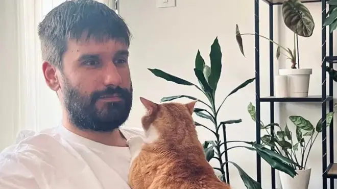 Bojan, mladić u beloj majici, sa narandžastom mačkom u krilima 