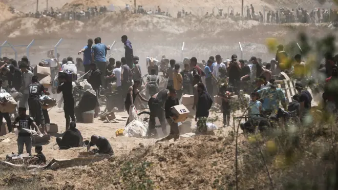 فلسطينيون يحملون مساعدات تلقوها من مؤسسة غزة الإنسانية قرب معبر نتساريم وسط قطاع غزة، في 29 مايو/أيار 2025
