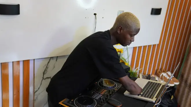Deejay Bankyroy demonstrating how he operates his disc jockey equipment despite his lower arms being amputated.